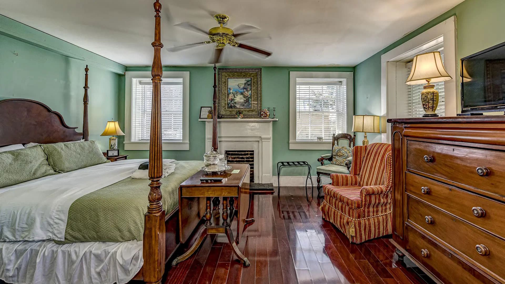 A cozy bedroom featuring a four-poster bed, hardwood floors, and vintage furnishings.
